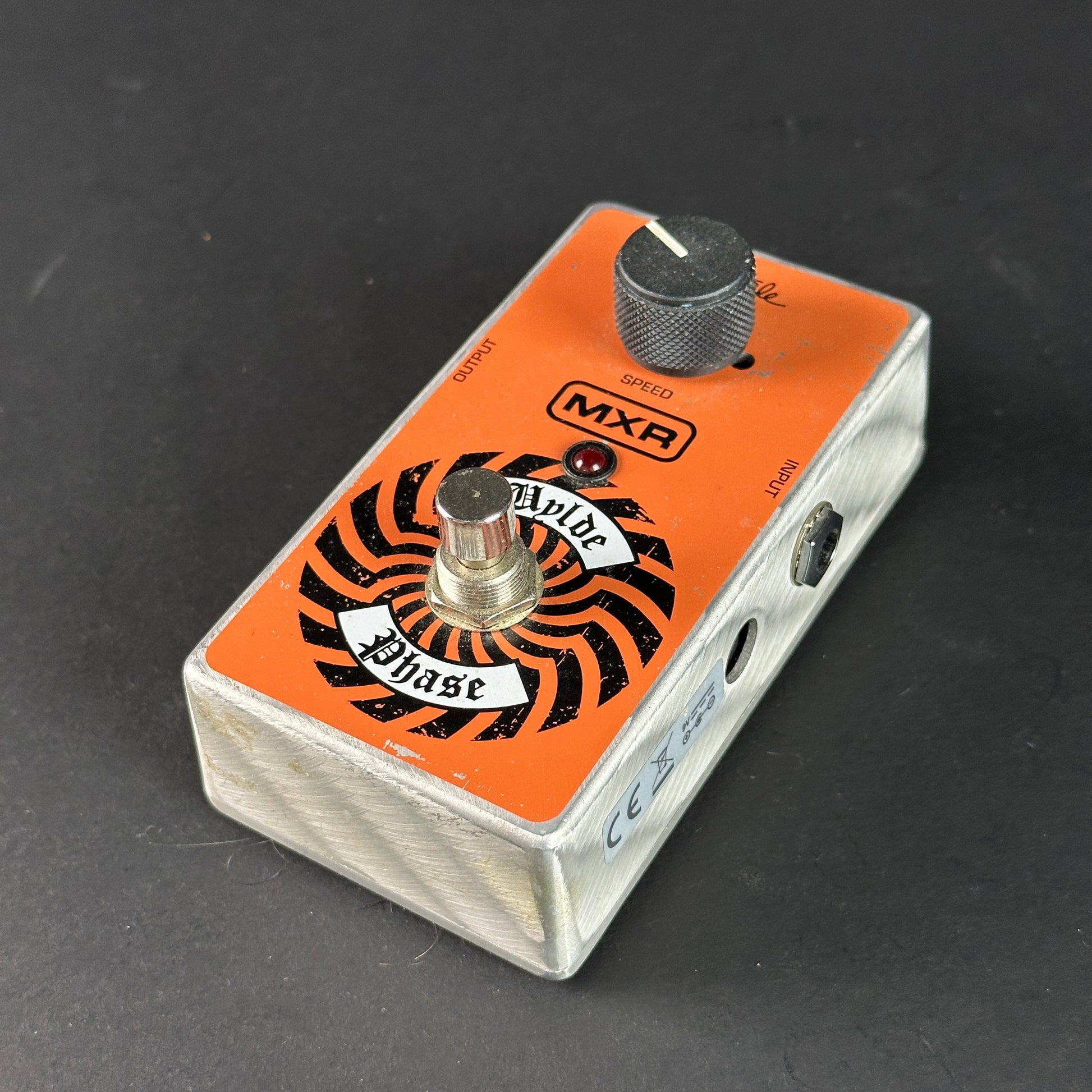 Guitar effects pedal with orange and black design on a dark background