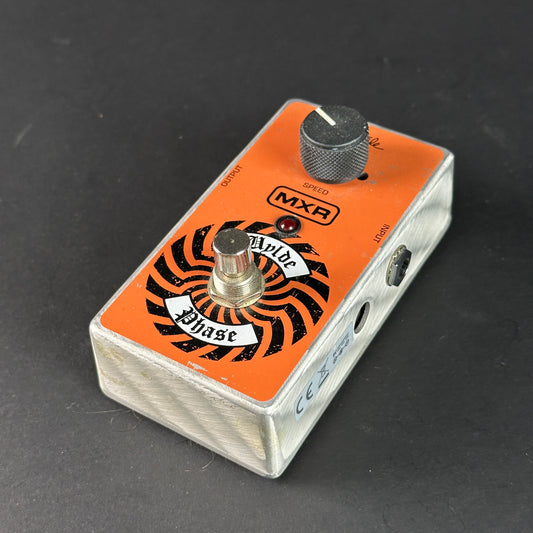 Guitar effects pedal with orange and black design on a dark background