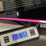 Guitar on a digital scale displaying weight, with a pink object in the foreground.