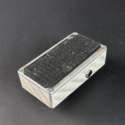 Metallic rectangular box with textured black top on a dark background