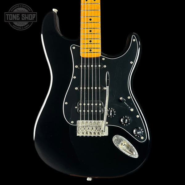 Black electric guitar with a blonde fretboard on a black background, featuring the Tone Shop logo.