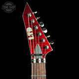 Close-up of a red electric guitar headstock with tuning pegs on a black background, featuring 'Tone Shop' branding.