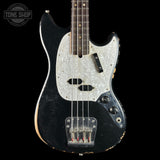 A vintage-style electric bass guitar with a black body, distressed finish, and a white marbled pickguard, shown against a solid black background. A Tone Shop logo is visible in the top-left corner.