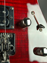Close-up of a red electric guitar with control knobs and bridge.