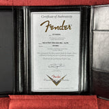 An open black leather Fender certificate folder displaying a Certificate of Authenticity insert for a Fender Stratocaster guitar.