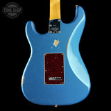 The back of a blue electric guitar with a distressed finish, featuring a dark red pickguard and a yellow maple neck, shown against a black background.