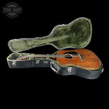 Acoustic guitar in a hard-shell case with 'Tone Shop' logo.