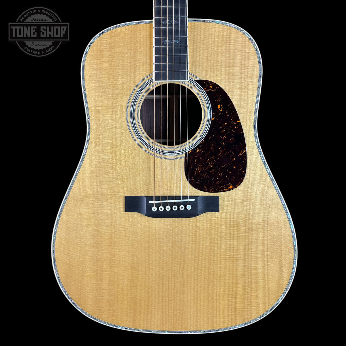 Acoustic guitar with a visible brand logo on a black background