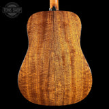 Close-up of a wooden acoustic guitar back with 'Tone Shop' logo.