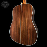 Back view of a wooden acoustic guitar with 'Tone Shop' logo in the corner.