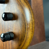 Wooden object with two black knobs on a blurred background