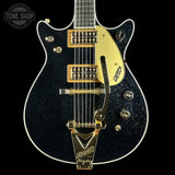 Black electric guitar with gold hardware on a black background, featuring the Gretsch logo.