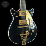 Black electric guitar with gold hardware on a black background, featuring the 'Tone Shop' logo.