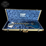 Blue electric guitar in an open case with 'ESP USA' branding on a black background.