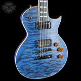 Blue electric guitar with a wavy finish on a black background, featuring the Tone Shop logo.