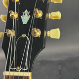 Close-up of a guitar headstock with tuning pegs and brand logo.