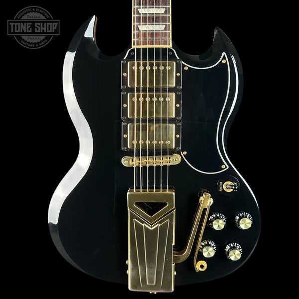 Black electric guitar with gold hardware on a black background, featuring 'Tone Shop' logo.