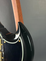Close-up of a black guitar case with gold hardware on a gray background