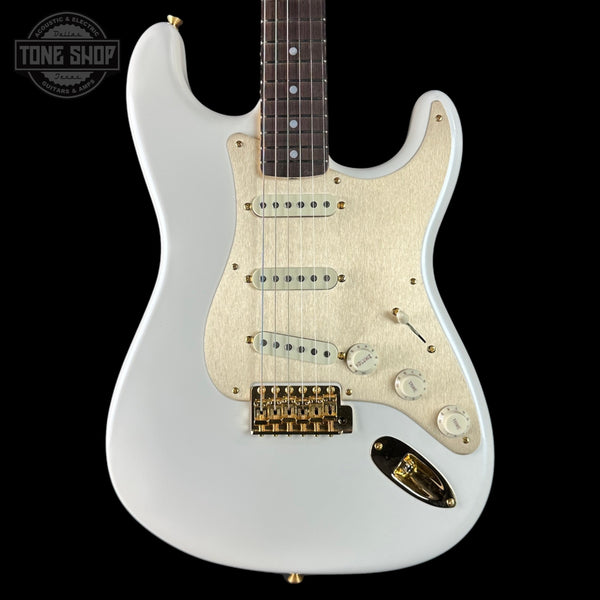 White electric guitar with gold hardware on a black background