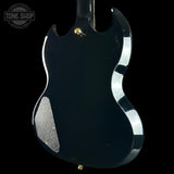 Close-up of a black electric guitar's body with a visible brand logo in the corner.