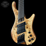 Wooden electric bass guitar with a black background, featuring the Tone Shop logo.