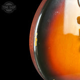 Close-up of a guitar's body with a visible brand logo in the corner.