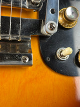 Close-up of a guitar's control panel with knobs and switch.