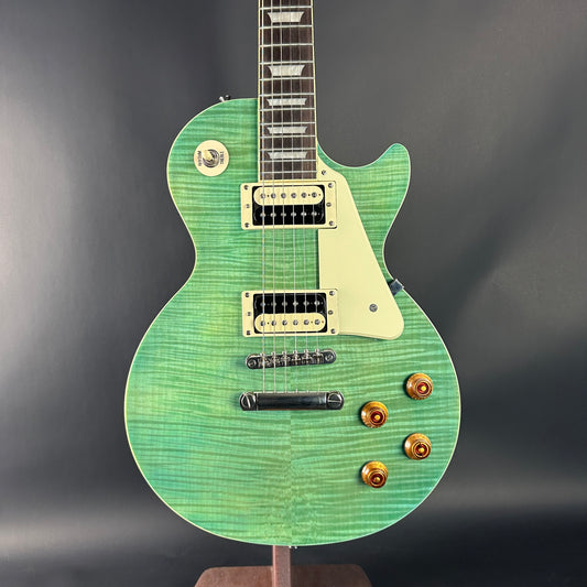 Green electric guitar on a stand against a dark background