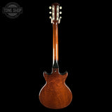 Back view of a wooden electric guitar on a black background with 'Tone Shop' logo.