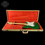 Green electric guitar in an open case with red interior, Tone Shop logo visible.