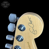 Guitar headstock with 'Fender' logo and signature on a black background