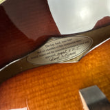 Close-up of a guitar neck with a label on a wooden guitar body.
