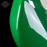 Close-up of a green guitar with white pickguard, brand 'Tone Shop' visible.