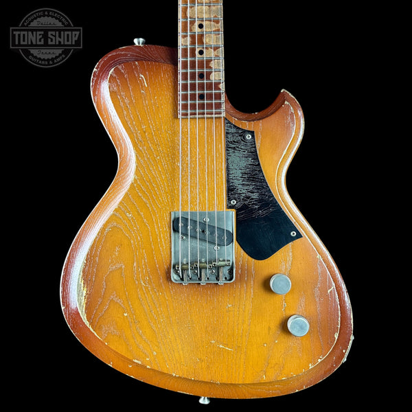 Worn electric guitar with a visible brand logo on a black background