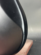 Close-up of a black car mirror with visible scratches on a gray background