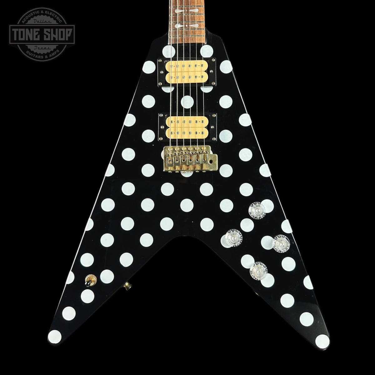 Black electric guitar with white polka dot design on a black background, featuring the Tone Shop logo.
