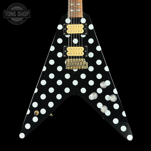 Black electric guitar with white polka dot design on a black background, featuring the Tone Shop logo.