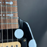 Close-up of a guitar's neck and headstock with a blurred dark background