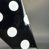 Close-up of a black die with white dots on a reflective surface