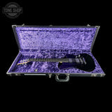Black electric guitar in a purple case with 'Tone Shop' logo.