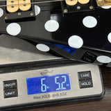 Guitar being weighed on a digital scale with a blue display showing weight.