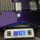Purple electric guitar on a digital scale displaying weight.