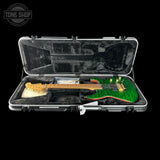 Green electric guitar in a black case with 'Tone Shop' logo.