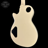 Beige electric guitar body with black pickguard on a black background, featuring 'Tone Shop' logo.