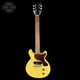 Yellow electric guitar with a black pickguard on a white background