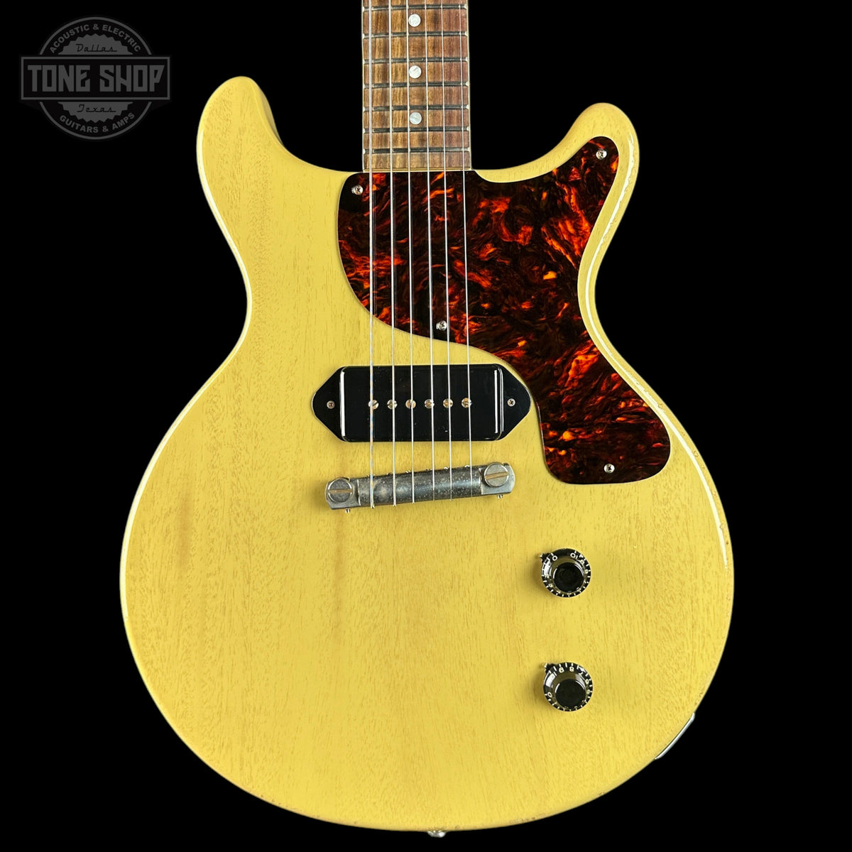 Yellow electric guitar with a flame maple neck on a black background, featuring the Tone Shop logo.