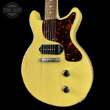 Yellow electric guitar with tortoiseshell pickguard on a black background, featuring 'Tone Shop' logo.