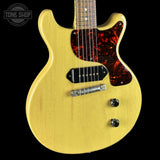 Yellow electric guitar with tortoiseshell pickguard on a black background, featuring 'Tone Shop' logo.