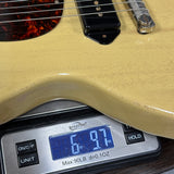 Beige electric guitar on a digital scale displaying weight.