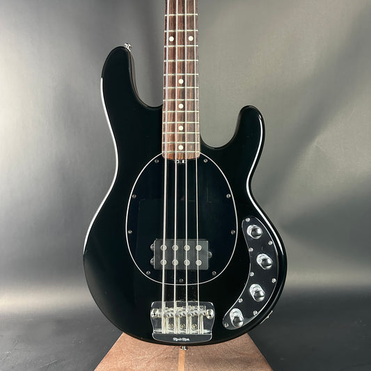 Black electric bass guitar on a gray background